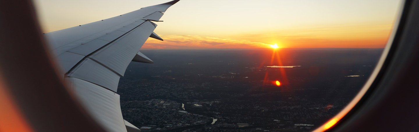 View from plane flying over city during sunset